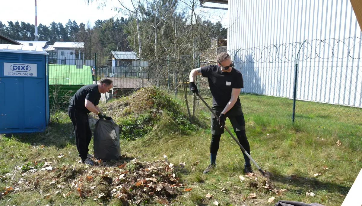 zwei Personen beim Arbeitseinsatz, eine Person harkt altes Gras zusammen, die andere packt es in einen Müllsack | © 	 Theodor Kubusch