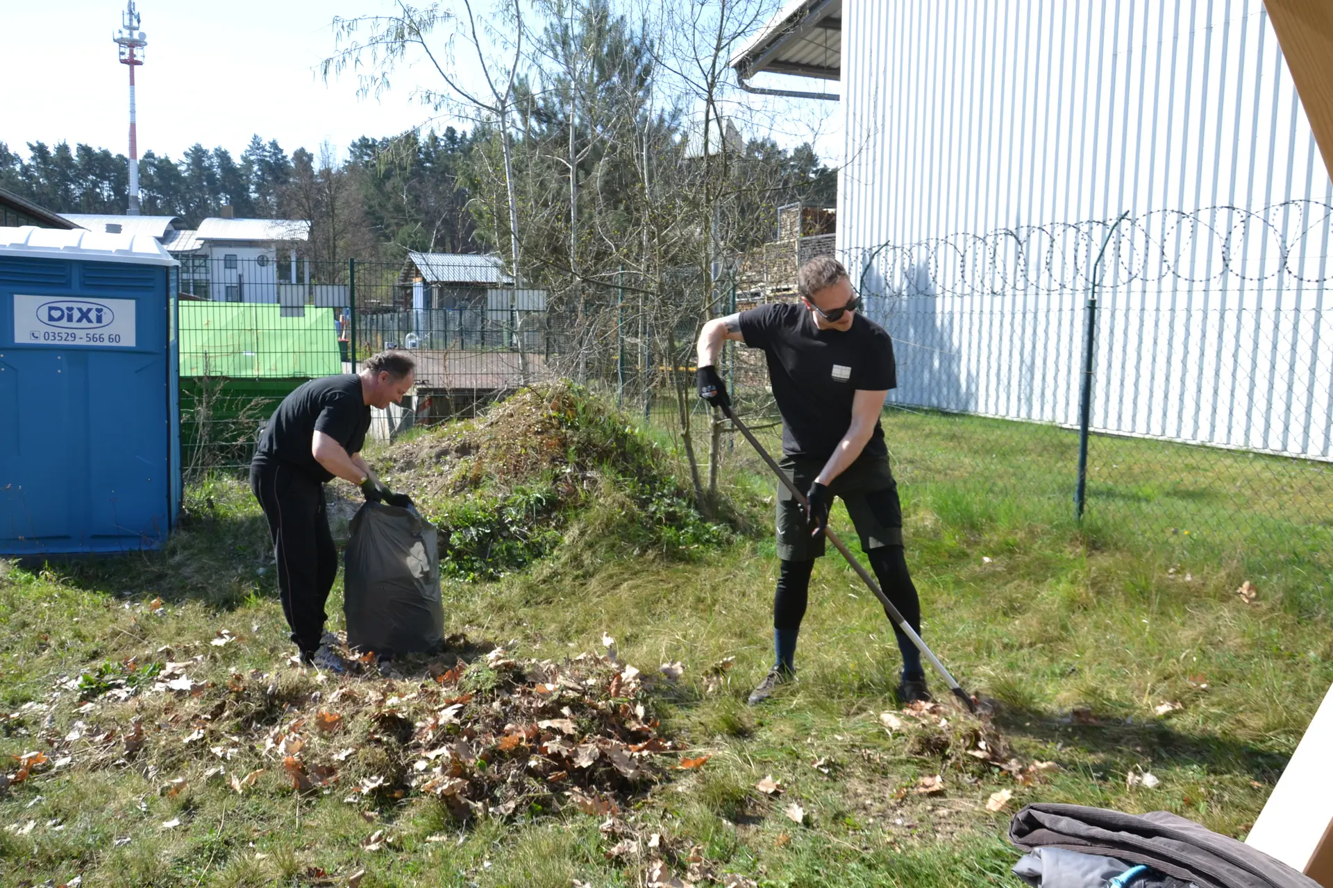 zwei Personen beim Arbeitseinsatz, eine Person harkt altes Gras zusammen, die andere packt es in einen Müllsack | © 	 Theodor Kubusch