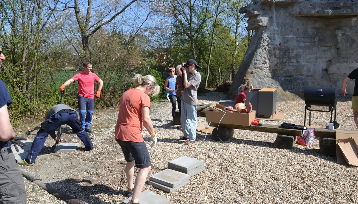 Mehrere Personen bereiten das Fundament des Grillplatzes vor; kleines Erdloch, Fundamentplatten liegen noch verstreut | © 	 Theodor Kubusch