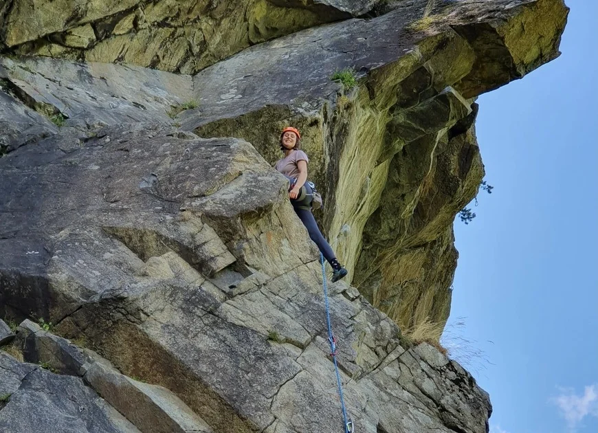 Hanna beim Klettern am Felsen. Sie steht auf einem Absatz und schaut nach unten. | © Theodor Kubusch